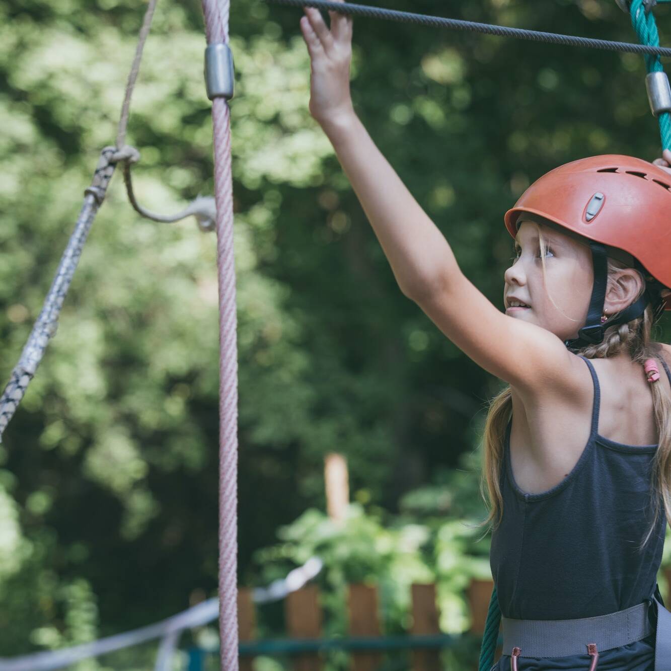 little girl make climbing in the adventure park.